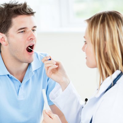 Caucasian female doctor taking a saliva sample of a male patient using cotton-bud