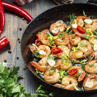 Freshly fried shrimps with herbs on old pan