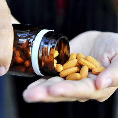 Mature woman with pills or vitamins on her hand