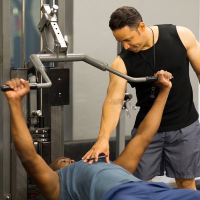 personal trainer helping client lift weights