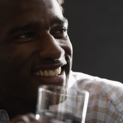 Close-up of a mid adult man holding a glass of water smiling