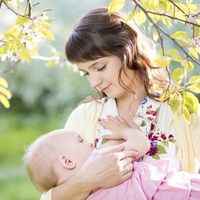 young mother breast feeding her baby girl at sunny day