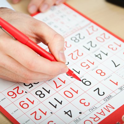 Office worker marking calendar with red pen