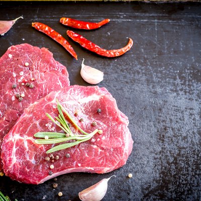 Fresh beef steaks with ingredients on the dark background