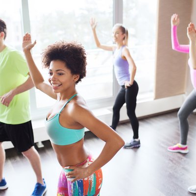 group of smiling people dancing in gym or studio
