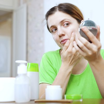 girl stares on face in mirror