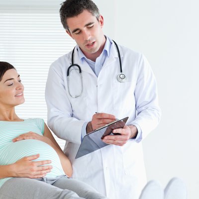 Pregnant woman lying down talking to her doctor