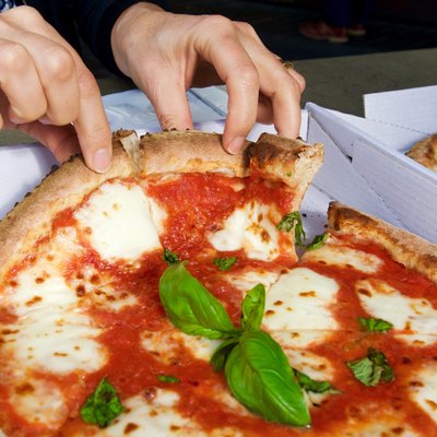 Fingers breaking apart pizza