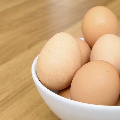 Eggs in white bowl on wooden table