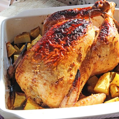 Baked chicken with potatoes in white ceramic bowl