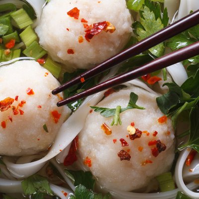 Asian soup with fish balls and chopsticks macro top view