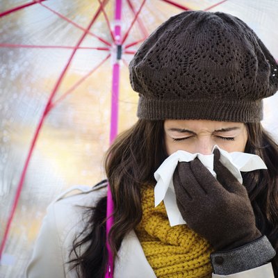 Woman coughing and blowing her nose in autumn