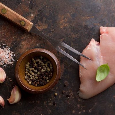 Raw chicken breast with rosemary, garlic and peppercorns, selective focus. Culinary cooking ingredients