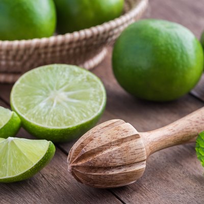 Wooden squeezer and lime on table
