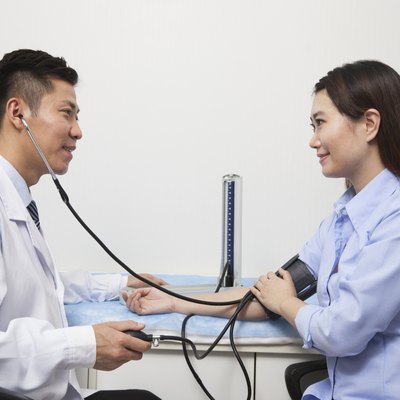 Young Woman Checking Blood Pressure With Male Doctor