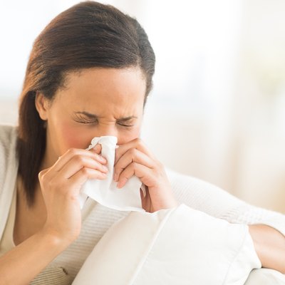 Woman Blowing Nose With Tissue At Home