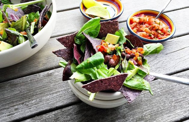 Side view of a taco salad with lettuce, pico de gallo, black beans, avocado and tortilla chips