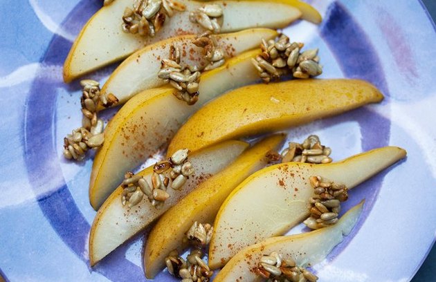 Top view of poached pears with candied sunflower seeds and cinnamon