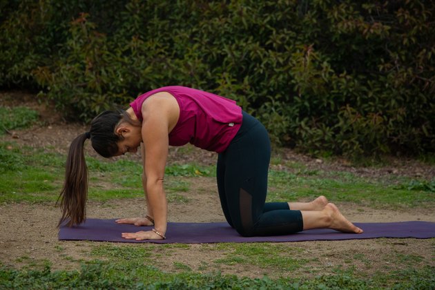Woman performing cat cow yoga pose.