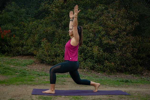 Woman performing high lunge with back leg bent.