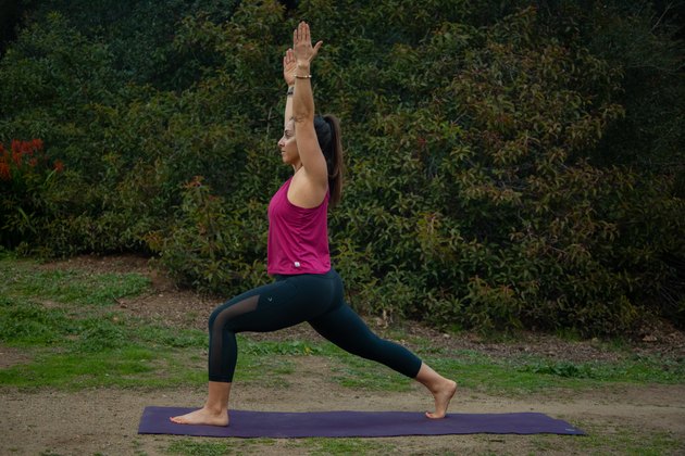 Woman performing high lunge on yoga mat.