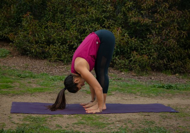 Woman performing standing forward fold.