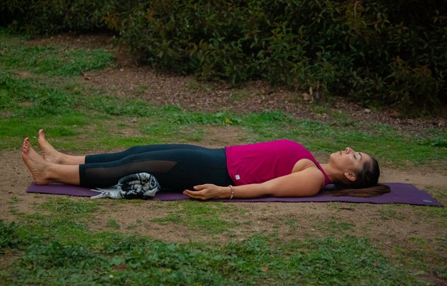 Woman lying in savasana outdoors.