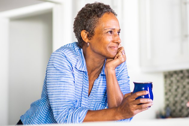middle-aged woman holding a cup of coffee looking content