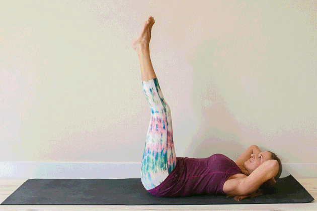 Woman demonstrating how to do legs-raised sit-ups for an at-home barre workout