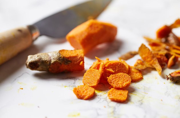 chopped turmeric on a cutting board with knife