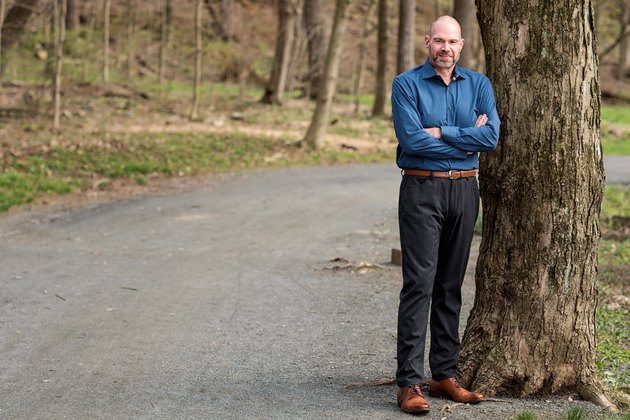 Scott stands by a tree.