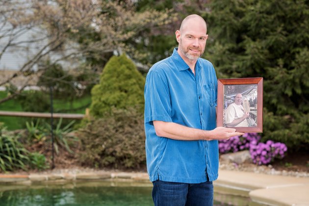 Scott holds an old photo of himself.