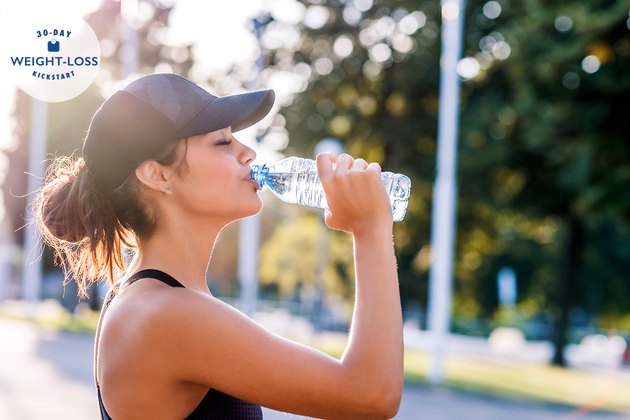 A woman doing intermittent fasting drinking water outside after a workout