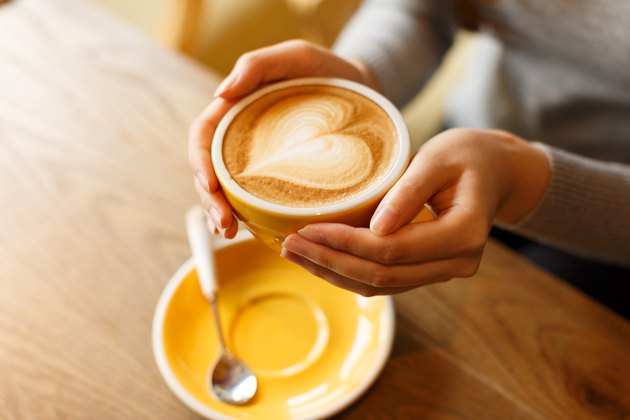 lady's hands holding cup with sth heart-shaped