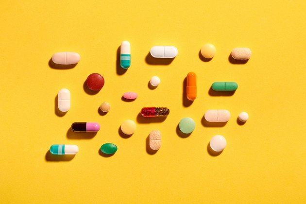 Colorful variety of vitamin and supplement pills on a yellow background