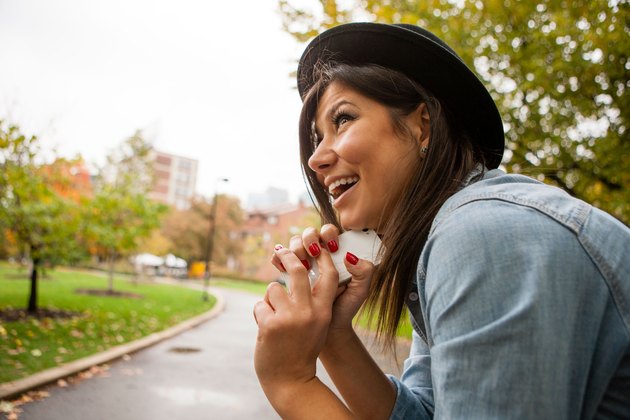 Woman sitting outside resting her Chin against her phone