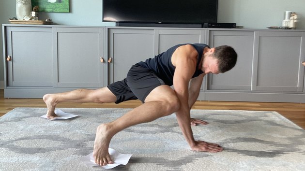 Man doing an ab workout with two pieces of paper in his living room