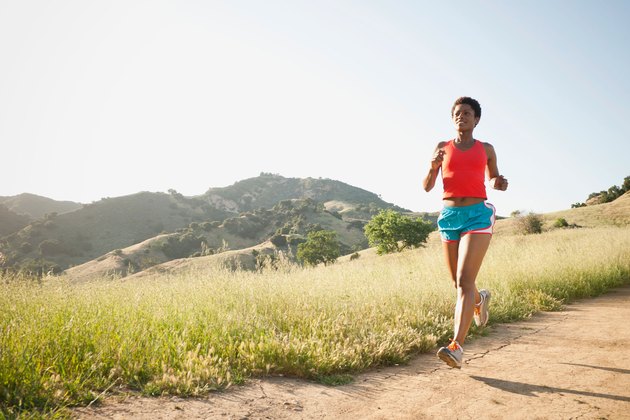 女子在丘陵小道上跑步，为超级马拉松训练