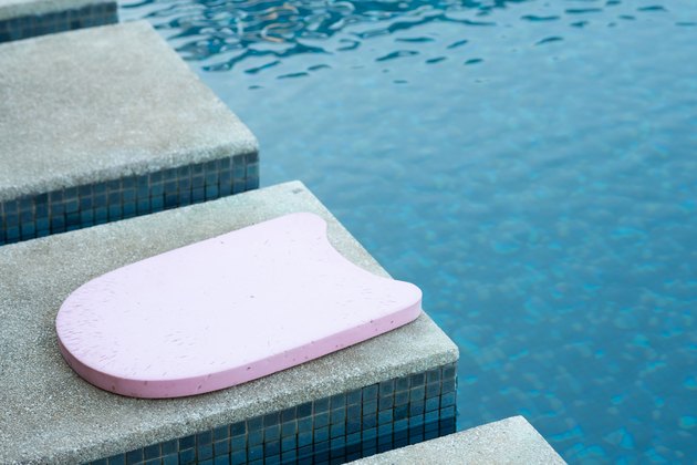 粉红色的踢脚板由池帮助教游泳课的一侧成为一个更好的游泳者