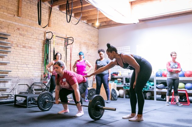 fitness professional and powerlifter Chrissy King helping a women with her deadlift form