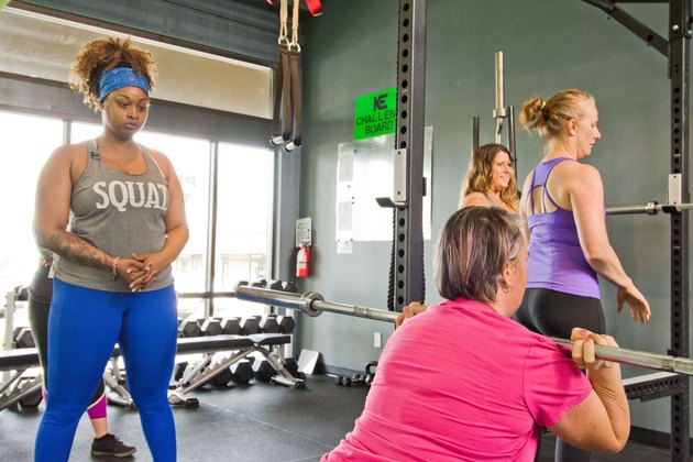 woman coaching another woman on proper front squat technique