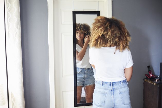 Woman looking in mirror at hairline