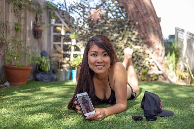 Kristina holds an old photo of herself on her phone