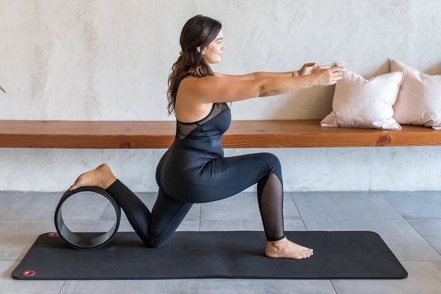 woman doing Low Lunge (Anjaneyasana) with a yoga wheel