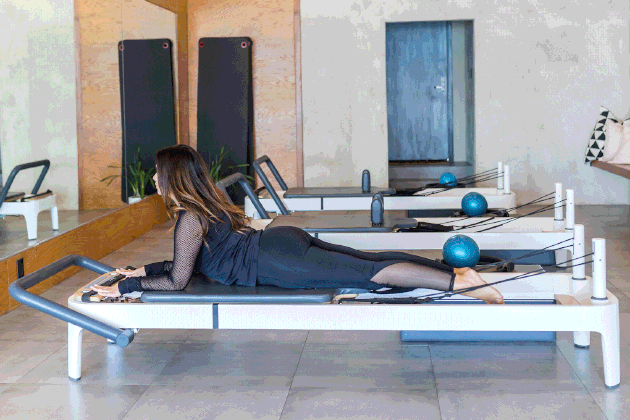 woman doing Single-Leg Kicks on a Pilates reformer