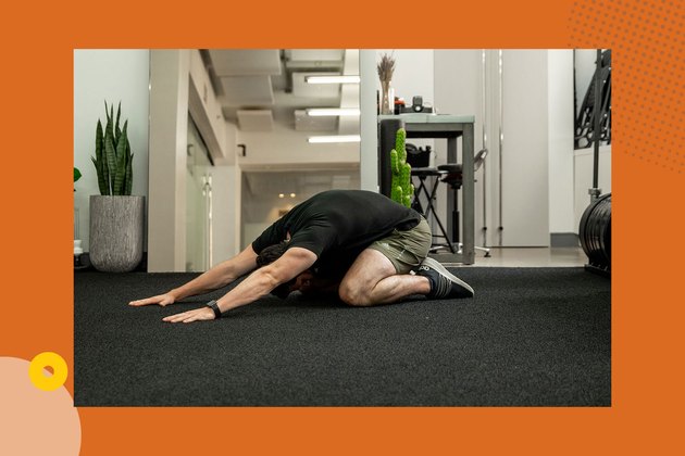 man wearing black shirt and green shorts doing child's pose back stretch at home