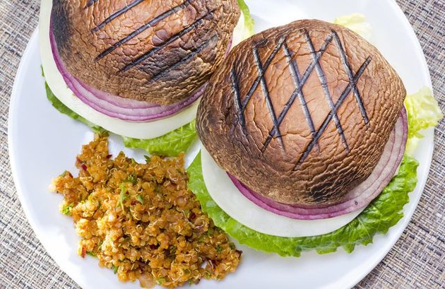 A white plate with two grilled vegetable burgers and a side of couscous