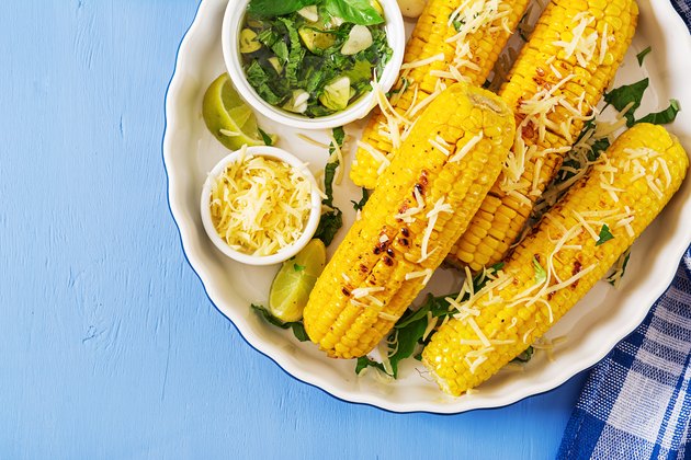 Delicious grilled corn with basil-garlic sauce and lime. Tasty food. Top view. Flat lay