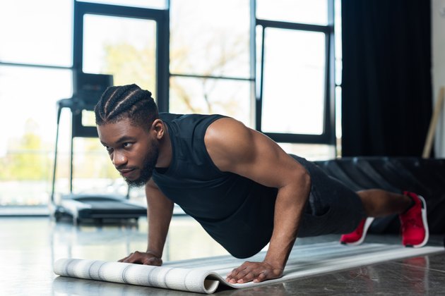 肌肉发达的非裔美国运动员在健身房做俯卧撑和看向别处