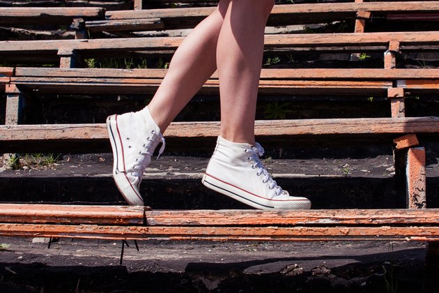 Woman model feet wearing sneakers walking down the bench